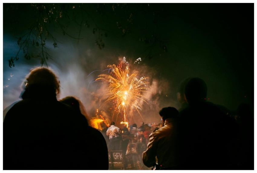 A crowd gathers under a night sky to watch colorfu