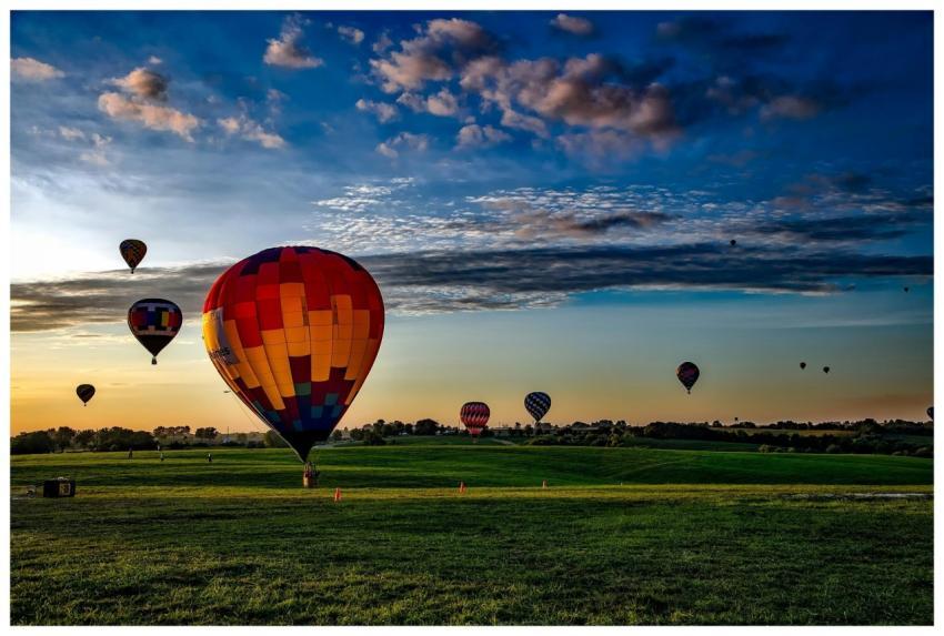 Vibrant hot air balloons take off at dawn over a r