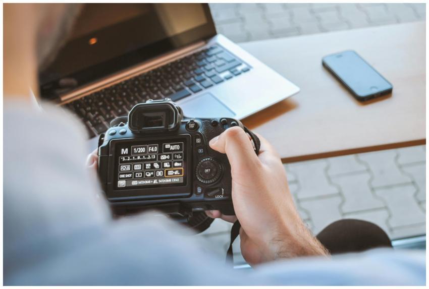 Close-up of hands holding DSLR camera at a workspa