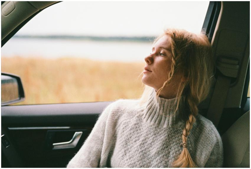 A thoughtful woman with braided hair gazes out a c