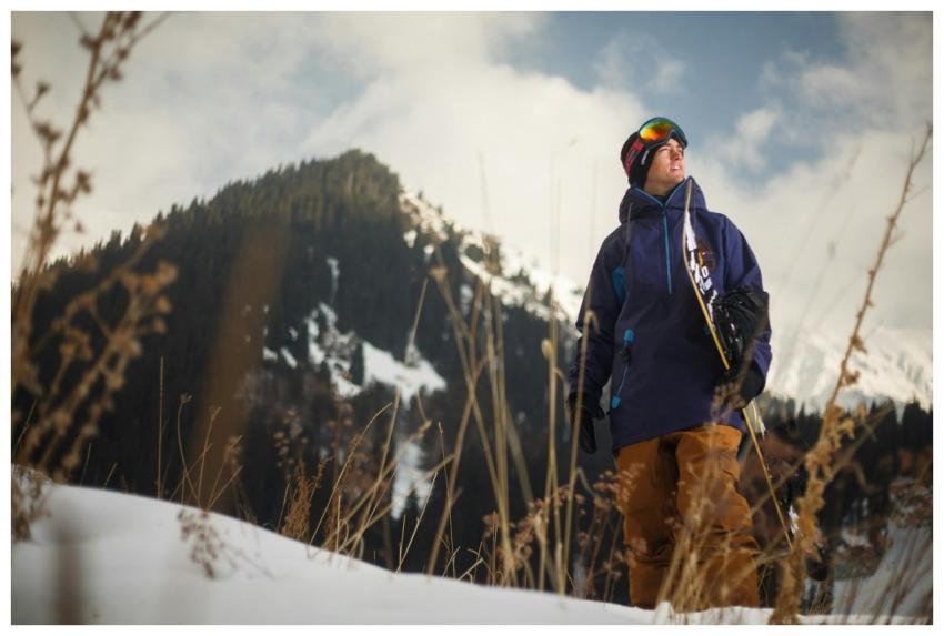 A snowboarder in winter gear with goggles enjoys t
