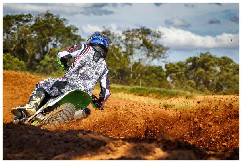 Motocross biker in racing gear kicks up dirt on an