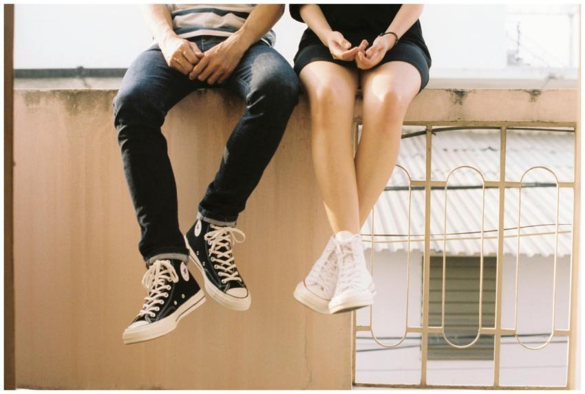 A relaxed couple sitting on a ledge, wearing styli