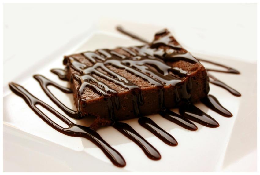 Rich chocolate brownie drizzled with syrup on a cl