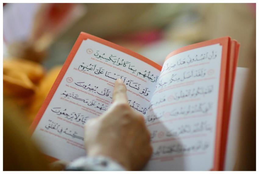 Close-up of a person reading an Arabic text, highl