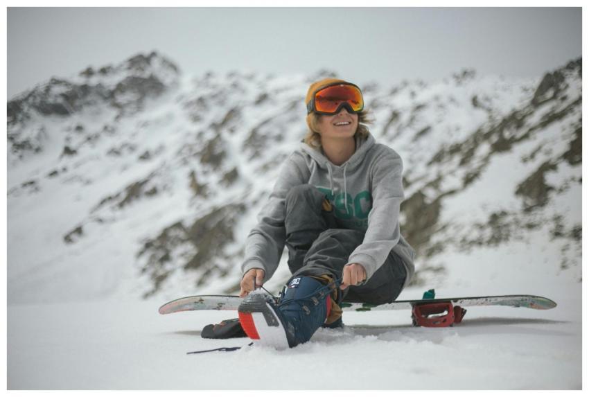 Woman snowboarder tying boots, enjoying a winter d
