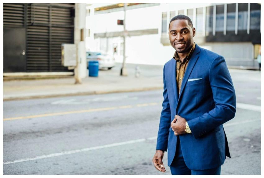 A confident businessman in a blue suit smiling out