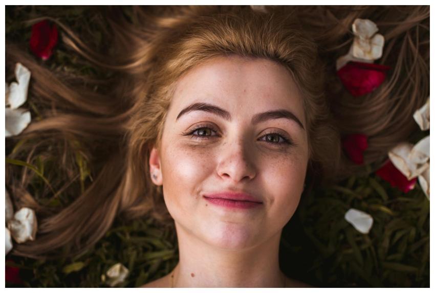Portrait of a smiling young woman with rose petals