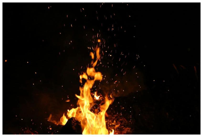 Mesmerizing campfire flames and sparks against a d