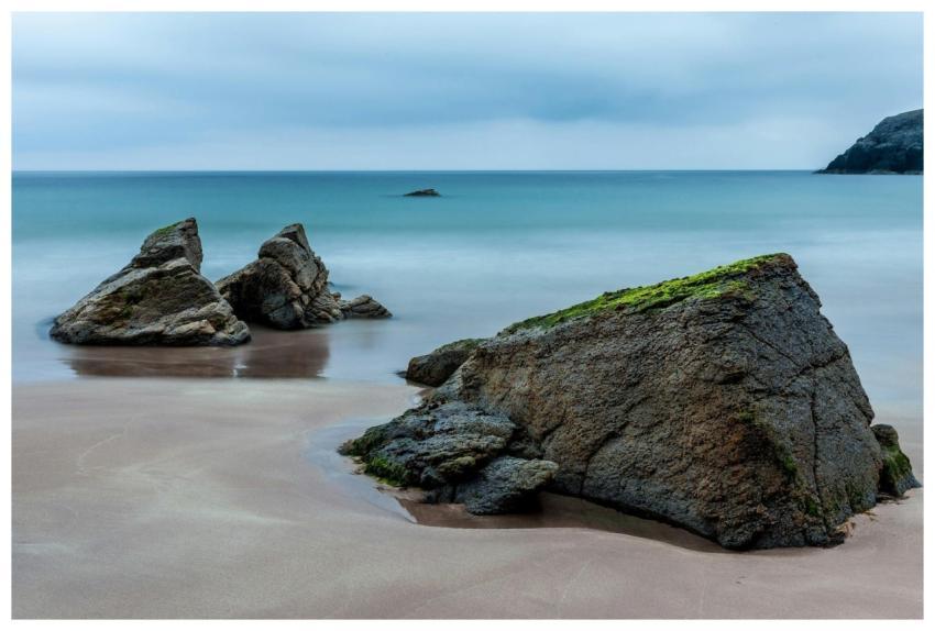 Peaceful beach with rocks and gentle waves under a