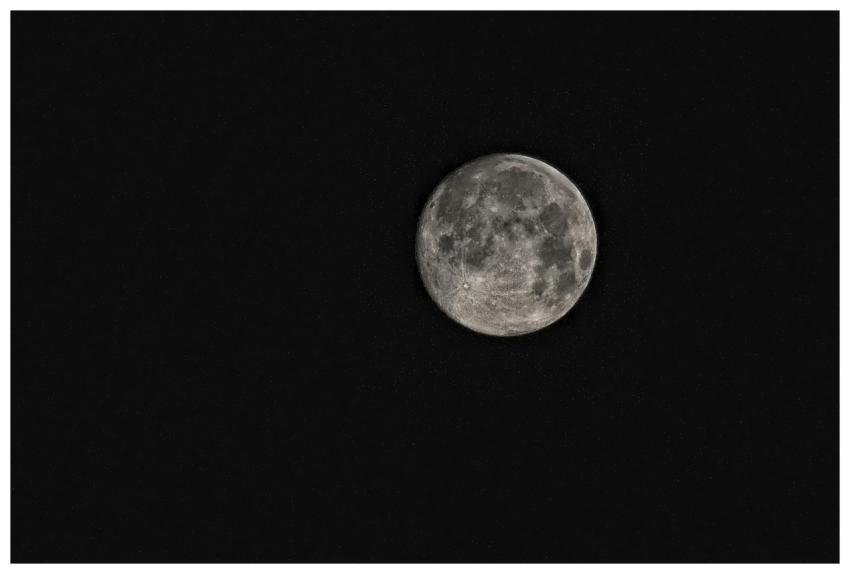 A detailed photograph of the full moon amidst a st