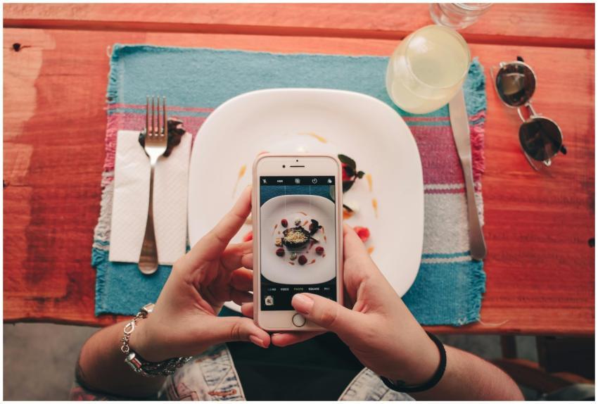 A woman takes a photo of a dessert with her smartp