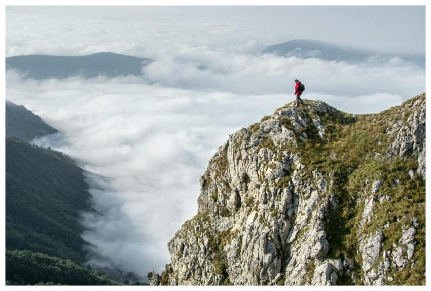Hiker in red standing on a rocky mountain summit e