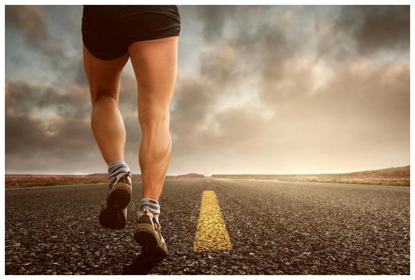 Runner's legs on a road during a sunset, symbolizi