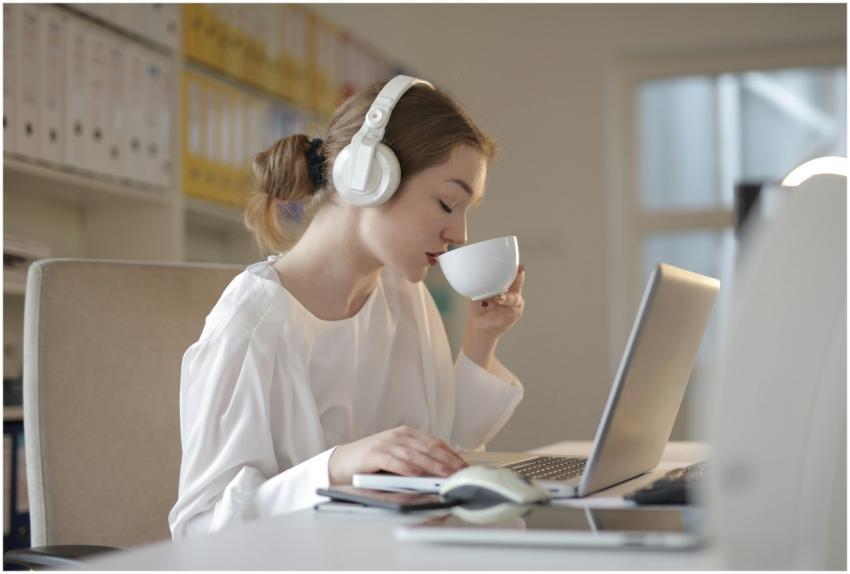 Woman wearing headphones and sipping coffee while