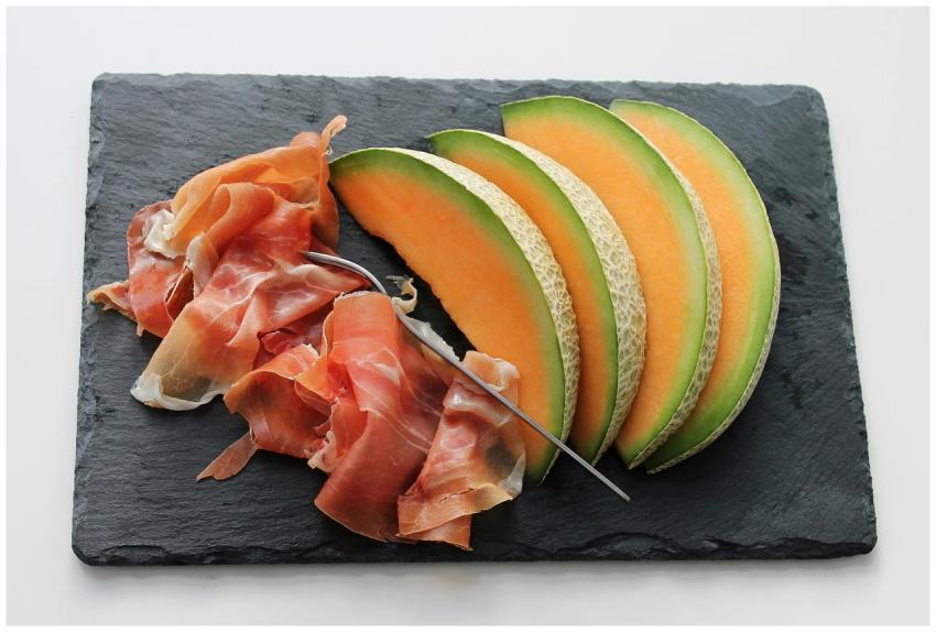 Freshly sliced melon with ham on a slate board, id