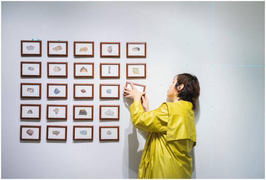 A curator arranging framed art in a modern exhibit