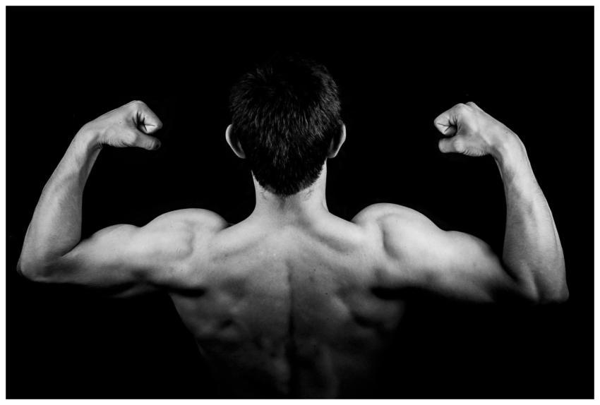 Black and white photo of a muscular man flexing ar