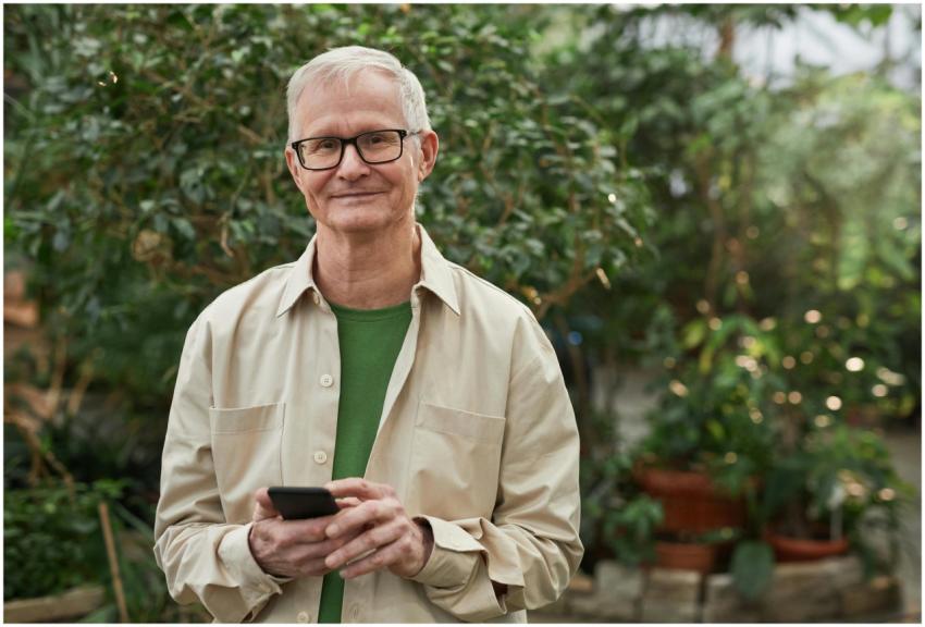 Senior man standing in a greenhouse garden, smilin