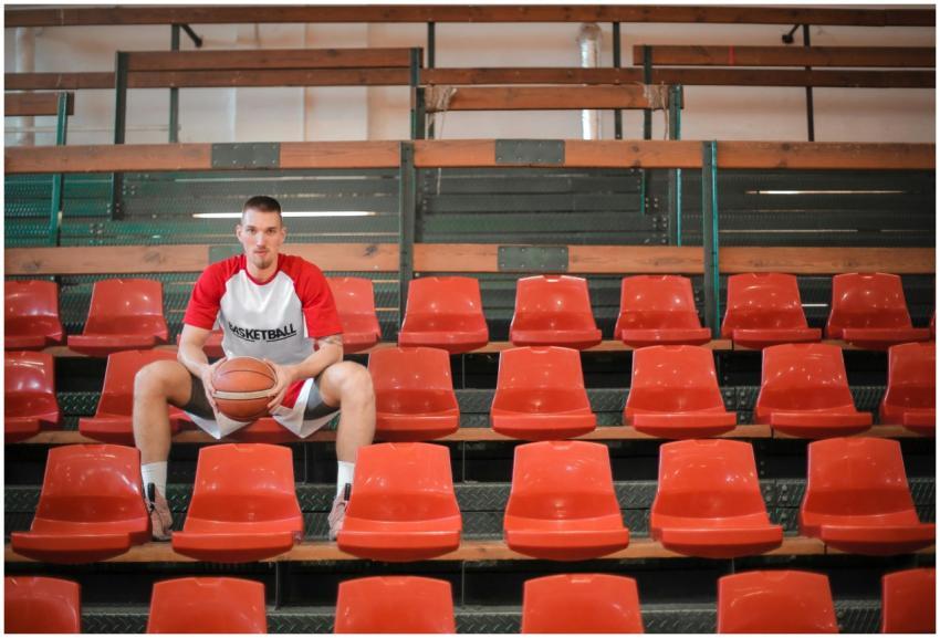 Young basketball player sitting confidently in emp