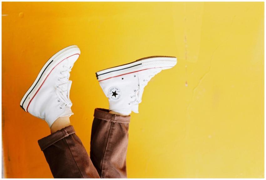 Upside down image of white sneakers against a vibr