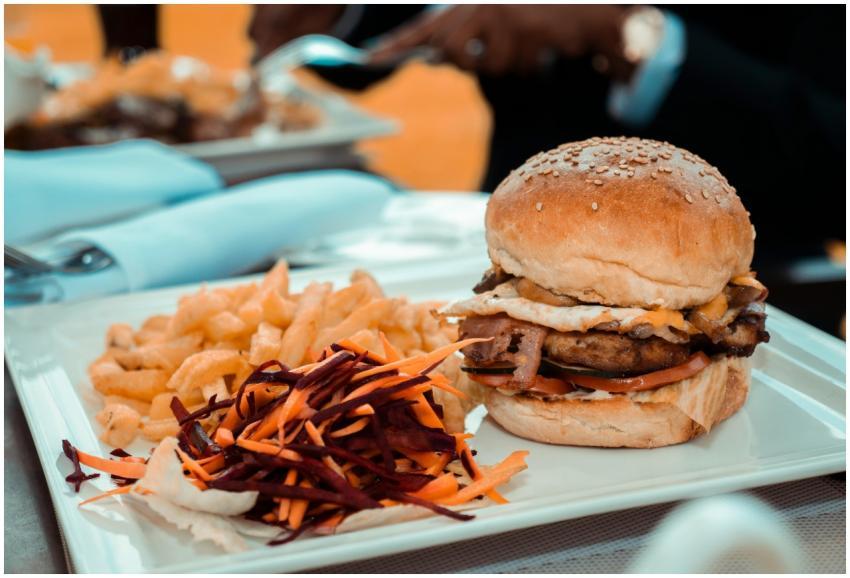 Close-up of a gourmet burger with fries and colorf