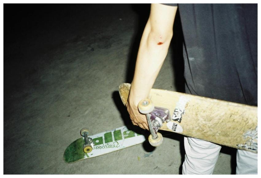 Close-up of a skateboarder holding a board at nigh