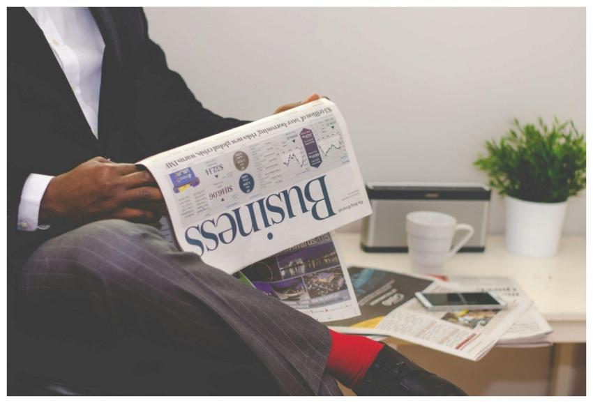 Businessman reading a financial newspaper at a des