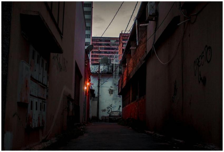 Dark urban alley at night with graffitied walls an