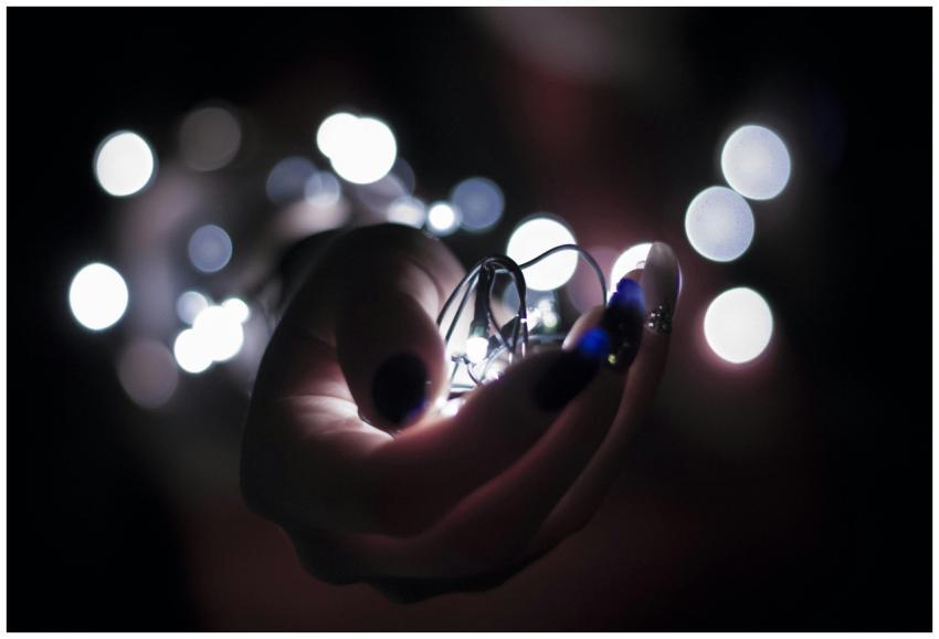 Close-up of a hand holding glowing string lights w