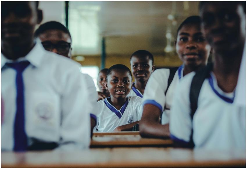 A group of Nigerian schoolchildren in uniform sitt