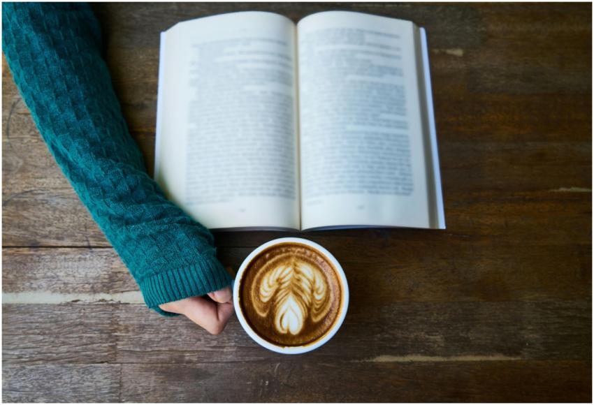 A cozy moment of reading a book with a latte art c