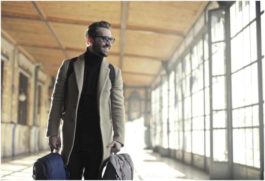 Smiling man in a winter coat with bags walking thr