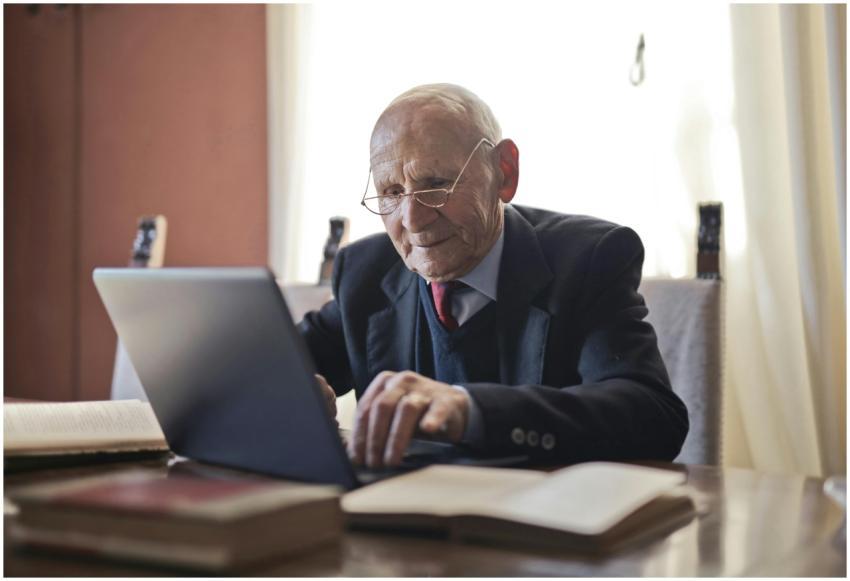 Focused elderly man in formal black suit and eyegl