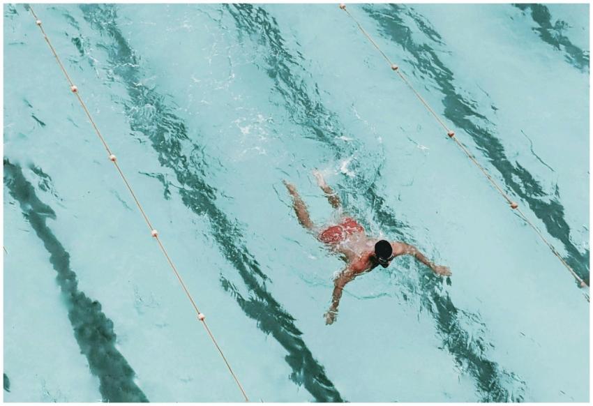 A person swimming in an outdoor pool with clear bl