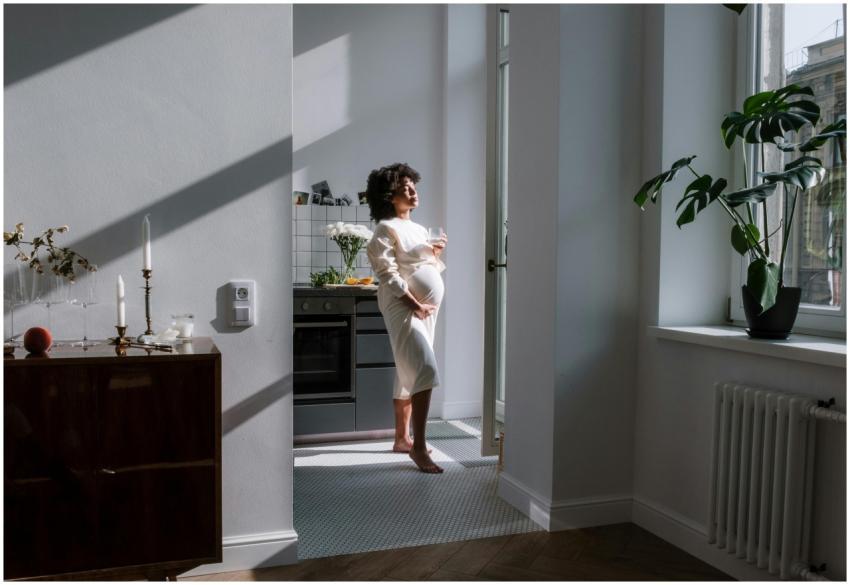 Expectant mother in a cozy sunlit kitchen, embraci