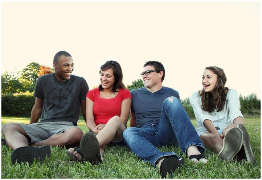 A group of young adults smiling while sitting on g
