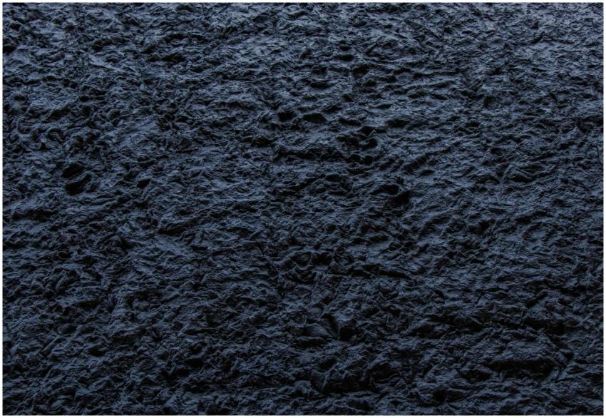 Close-up of a dark, rough textured stone surface p