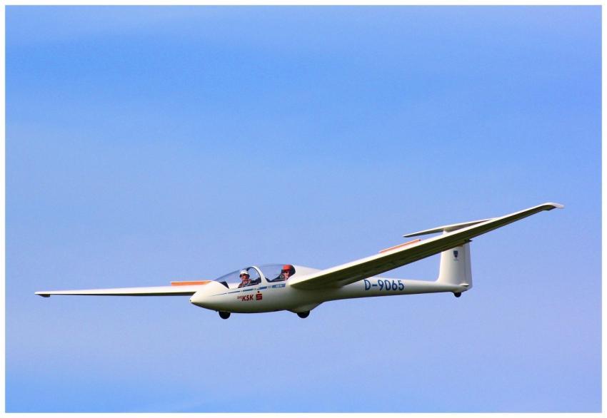 A two-seater glider flying gracefully against a ba