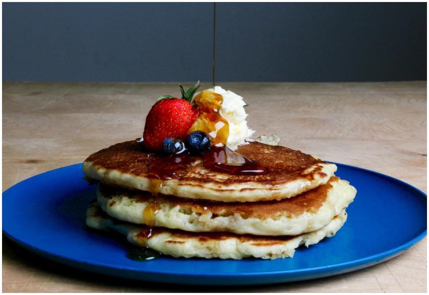 Stack of fluffy pancakes topped with syrup, strawb