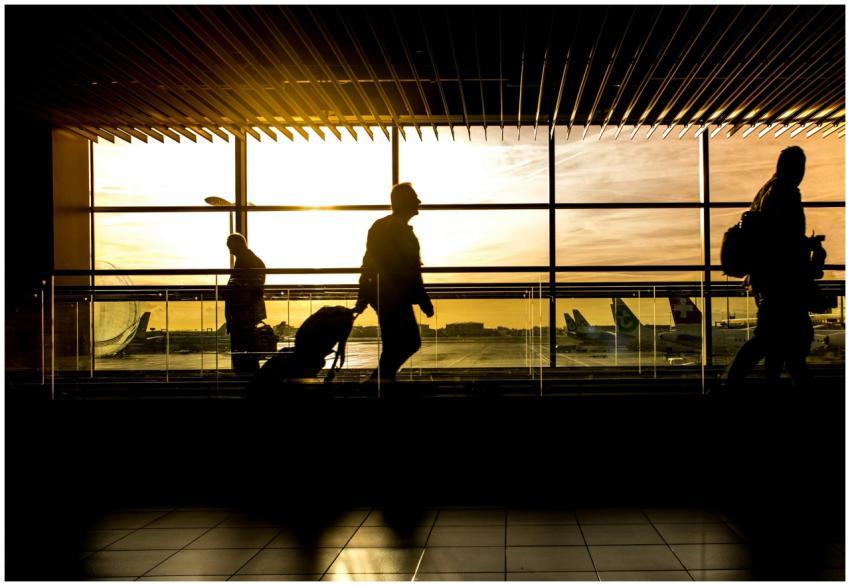 Travelers in silhouette pulling luggage at the air
