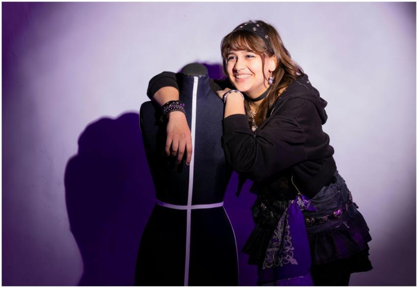 Smiling woman in edgy fashion poses with a mannequ