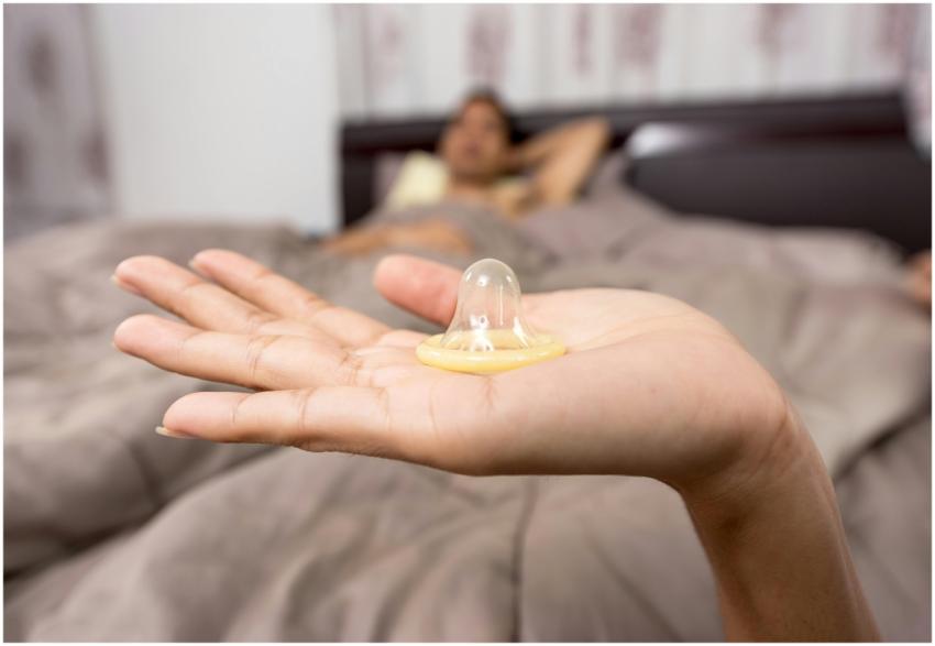 Close-up of hand holding condom, emphasizing safe