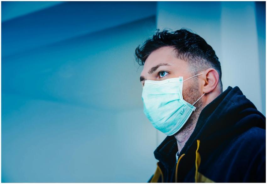 Side view of a man in a face mask indoors, with dr