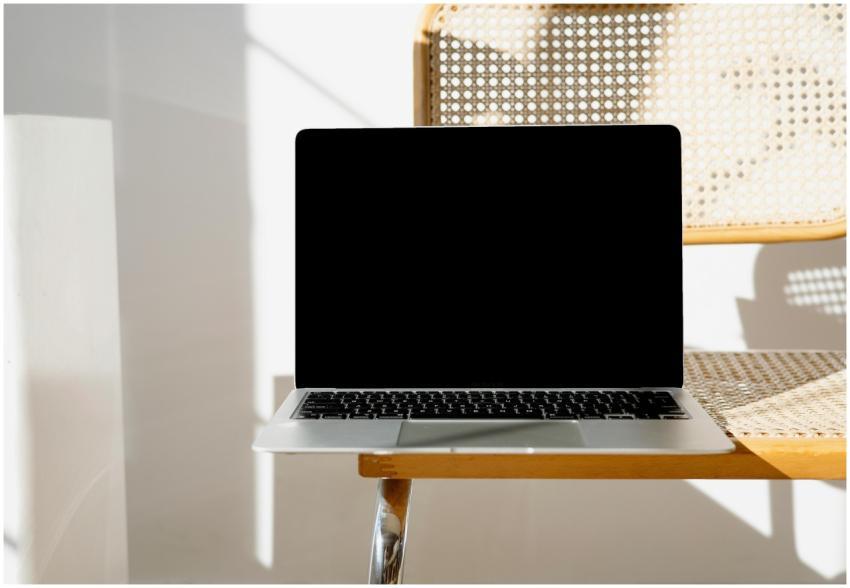 A sleek laptop sitting on a woven chair in a minim
