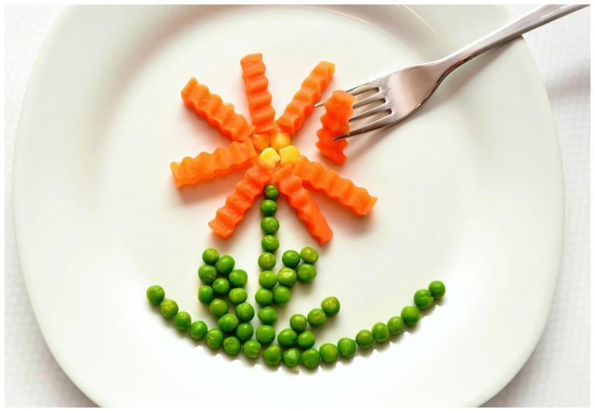 A playful flower made from carrots and peas on a w