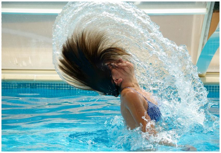 Woman splashing water with hair flip in a clear bl