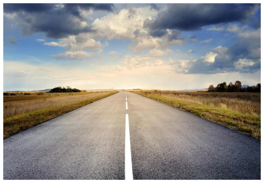 A long straight road stretches through fields unde