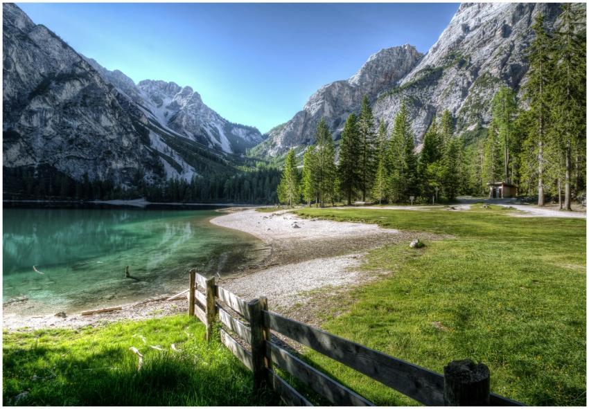 Serene mountain lake with green trees and a rustic