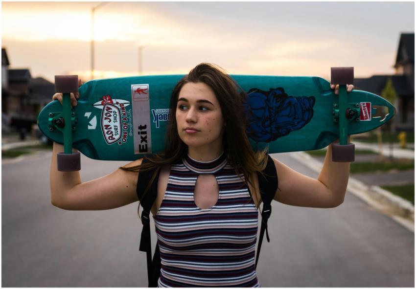 Teen girl carries a longboard skateboard on should